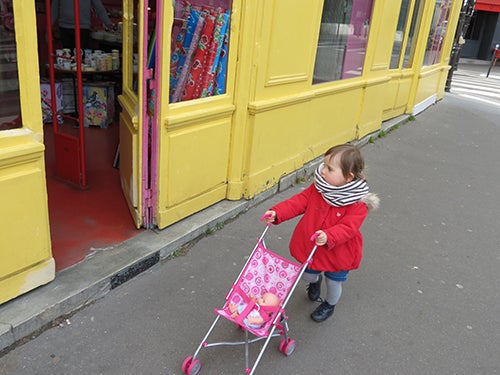 child with a toy stroller on the street