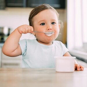 Bébé mange un laitage au fromage blanc