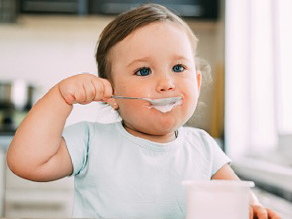 Bébé mange un laitage au fromage blanc