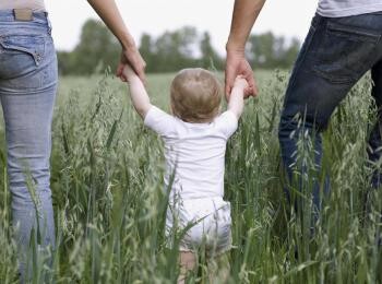Mom dad and baby walking in the field